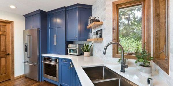 Modern kitchen with blue cabinets and large window.