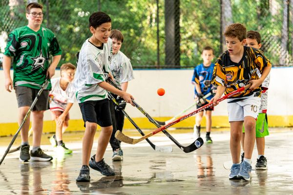 Kids playing street hockey with enthusiasm on an outdoor rink.