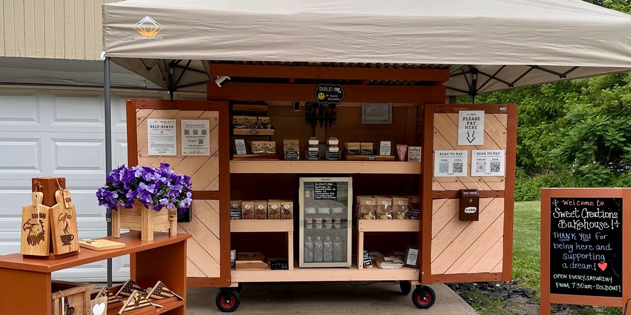 Self-serve outdoor bakery stand with packaged goods and payment options.