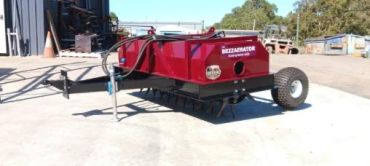 A red agricultural machine named Beezzerator on a farm.