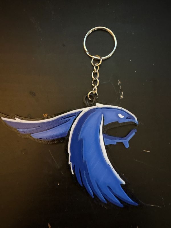 Blue bird-shaped keychain on a black surface.