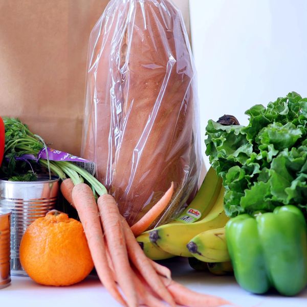 Fresh groceries including carrots, bananas, lettuce, bell peppers, an orange, and packaged bread.