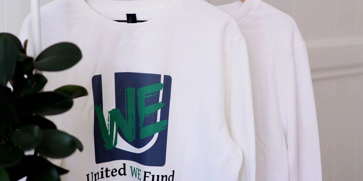 White sweatshirt with a "United WE Fund" logo displayed on a hanger.