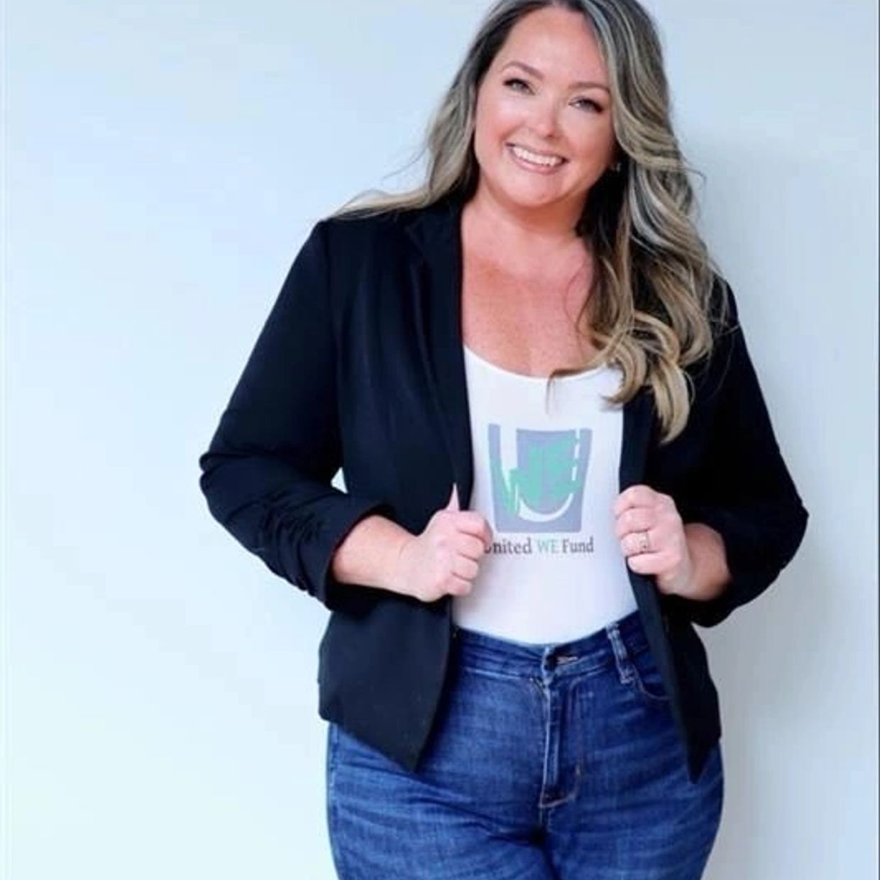 Smiling woman in a black jacket and jeans posing confidently.