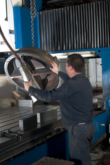 Factory worker using machine to move metal part.  - Industrial Photography by S&C Design Studios