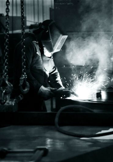 Welder with mask using torch.  - Industrial Photography by S&C Design Studios