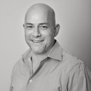 Smiling bald man in a casual shirt.