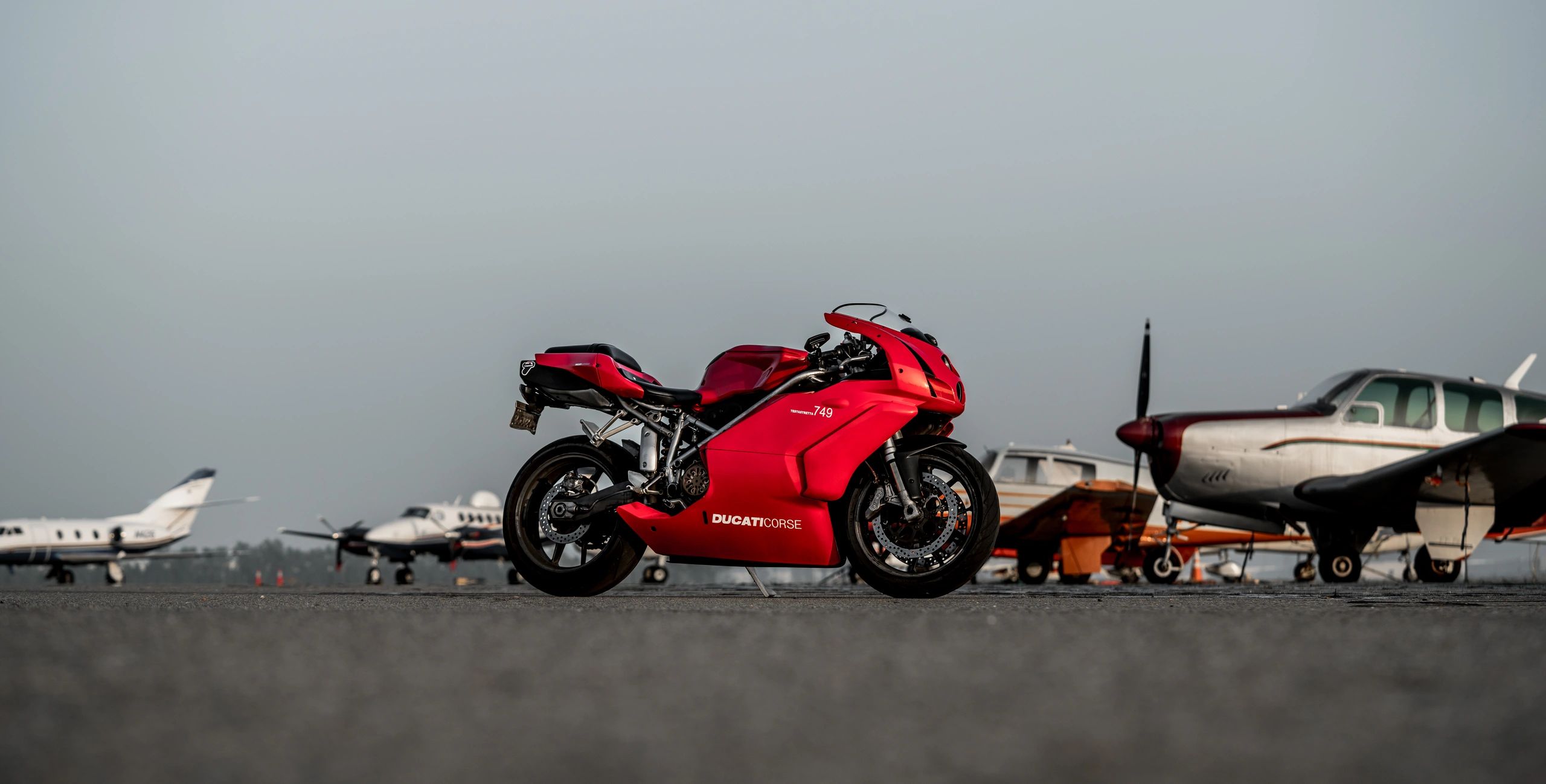 Red Ducati Motorcycle with Aircraft in the background