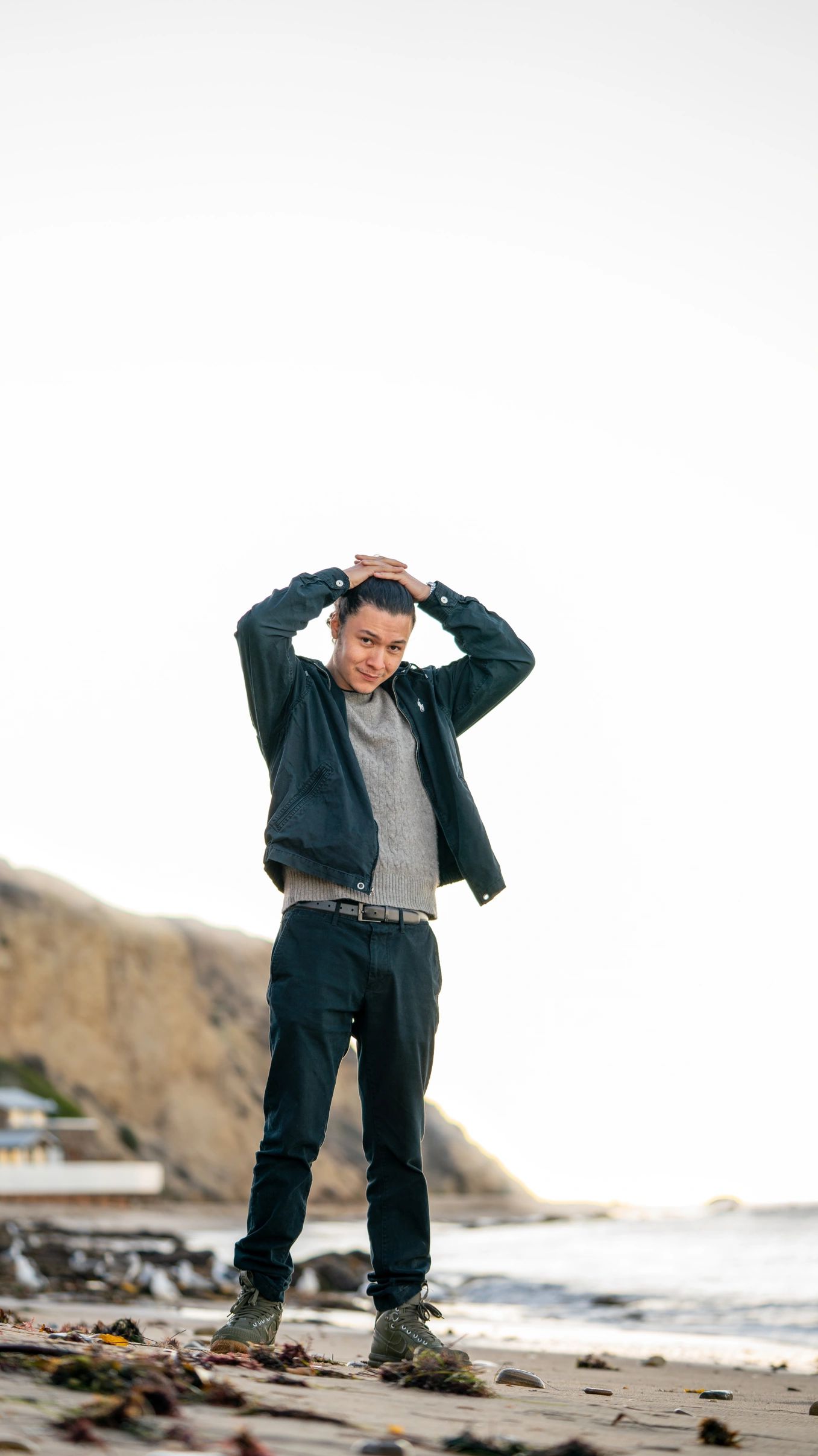 Male model standing on beach holding his hair