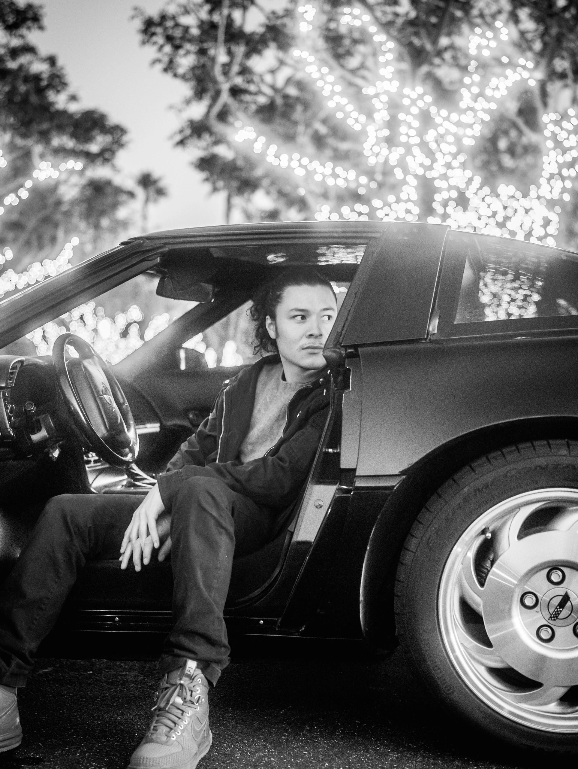 Male model sitting in his corvette with door open looking left black and white photo