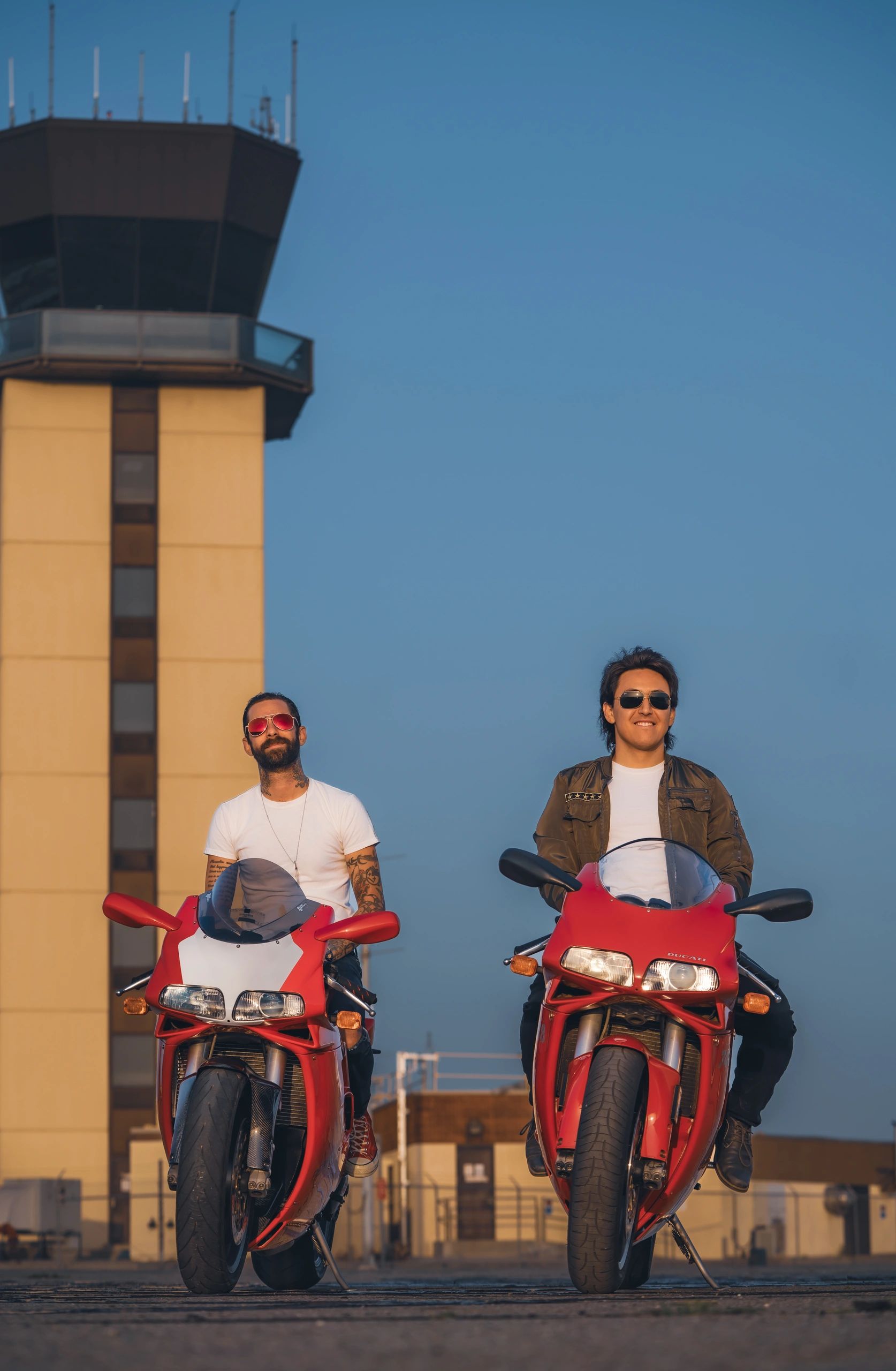 Men on Ducati motorcycles with radio control tower in the background