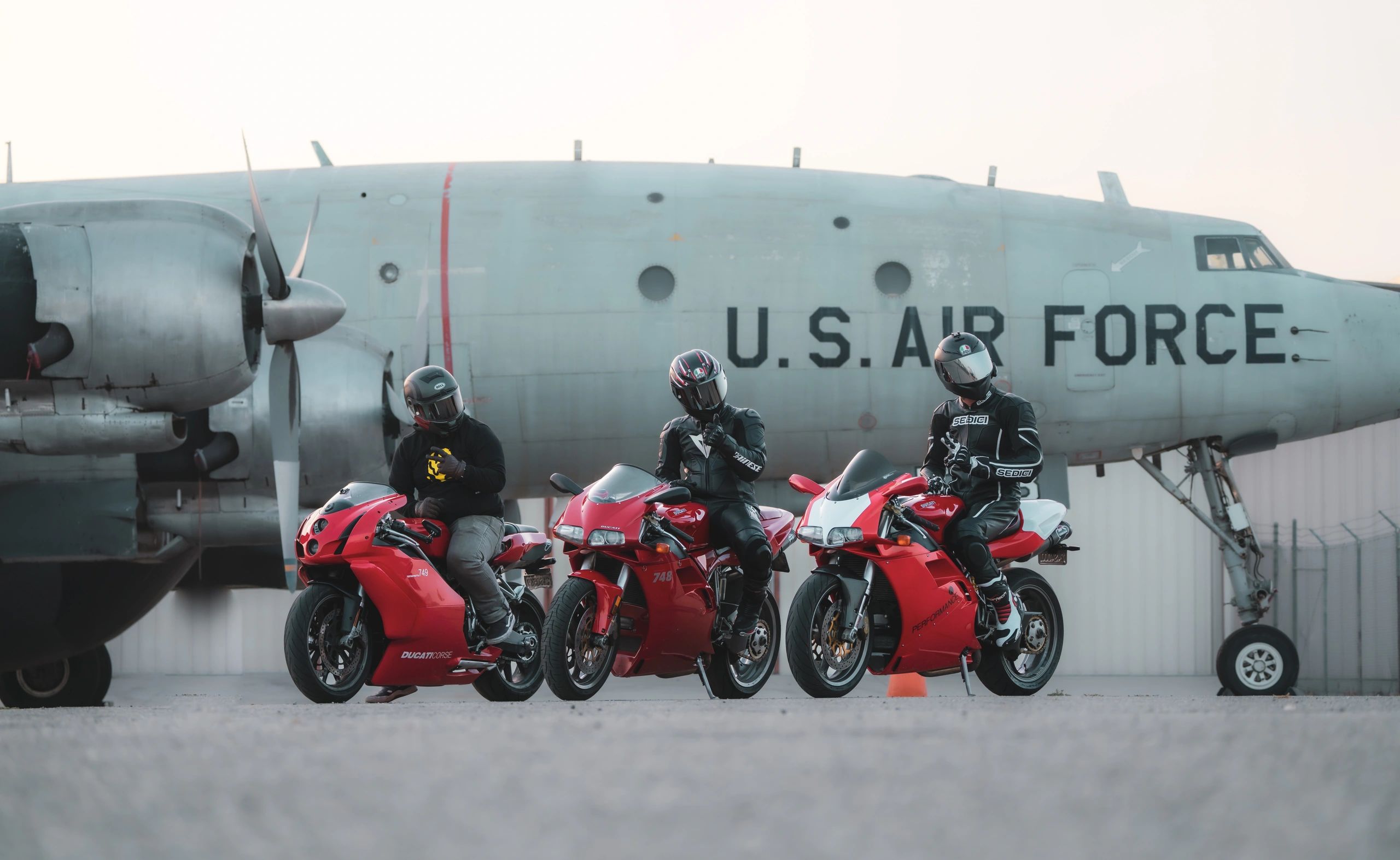 Men on Motorcycles all with red Ducatis US Aircraft in the background