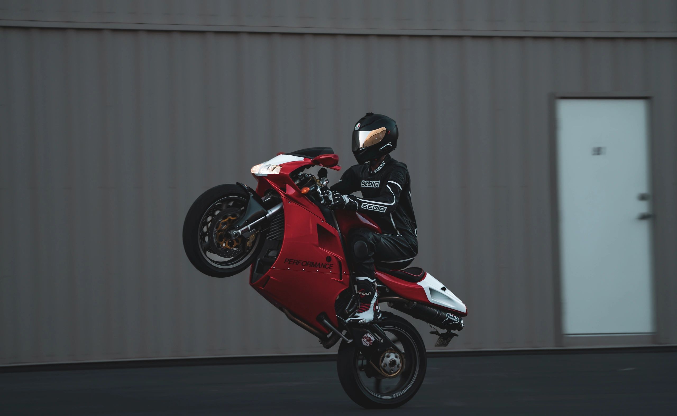 Red Ducati motorcycle rider doing a wheelie