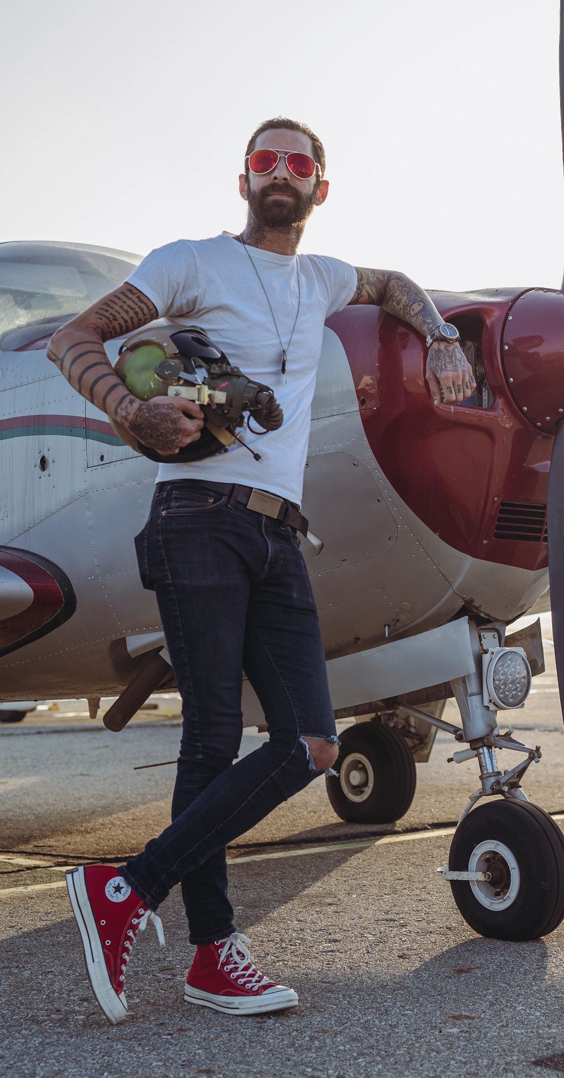 Male model with sunglasses leaning on aircraft