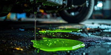 Bright green coolant leaking from a vehicle onto the garage floor.