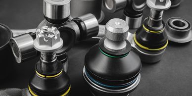 Close-up of metallic automotive ball joints with rubber seals on a dark background.