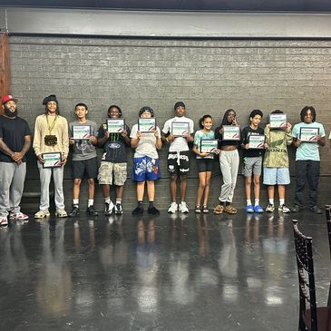 Group photo of young people holding certificates on stage.