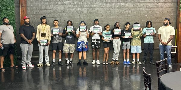 Group of kids and adults holding certificates, standing in a line.