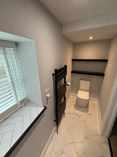Modern minimalist bathroom with white tiles and black accents.