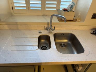 A clean kitchen sink with two basins and a modern faucet.