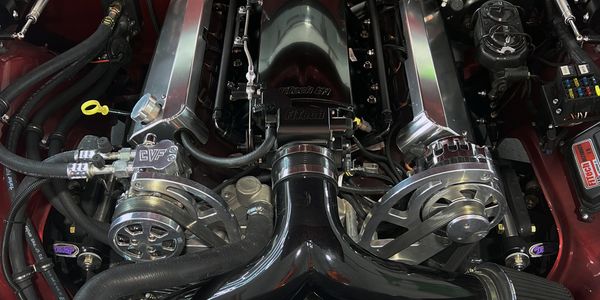 Close-up of a polished car engine with shiny chrome components and black hoses.