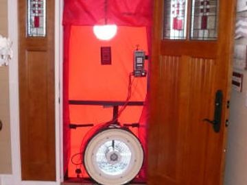 Blower door setup in entry door to test the home for overall air leakage.