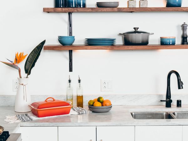 Kitchen countertop with sink, and plant, fruit bowl, shelves with plates