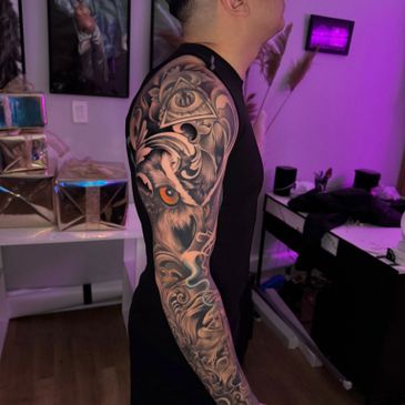 Man with a detailed sleeve tattoo featuring an eye and wolf design.