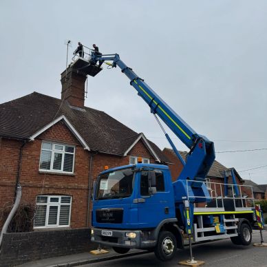 Workers on cherry picker fixing rooftop chimney.