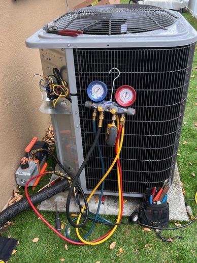 Air conditioning unit being serviced with gauges and tools attached.