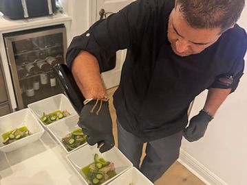 Chef carefully plating lime slices in white dishes wearing black gloves.
