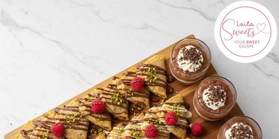 A selection of desserts including crepes, waffles, and chocolate mousse topped with berries.