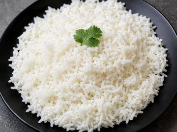 Plate of cooked white rice with a cilantro garnish.