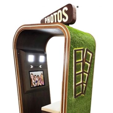 A modern photo booth with grass-textured exterior and illuminated window design.