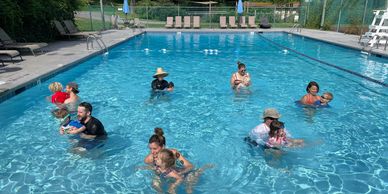Parents teaching children to swim in a pool on a sunny day.