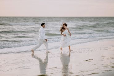 Couple in white running on the beach.