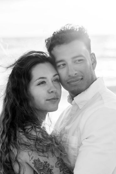 Couple embracing on the beach with warm expressions.