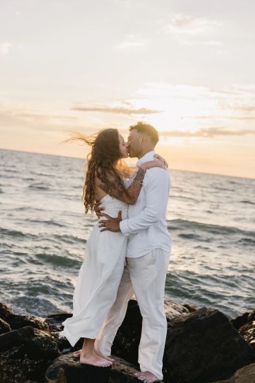 Couple kissing by the ocean at sunset.