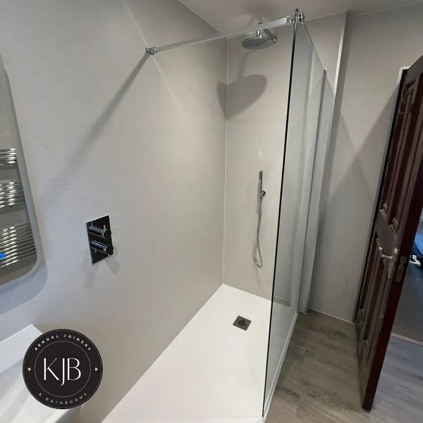 Minimalist walk-in shower with glass panel and sleek fixtures.