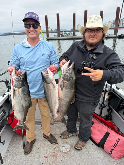 Two men proudly show off their large catches on a fishing boat.