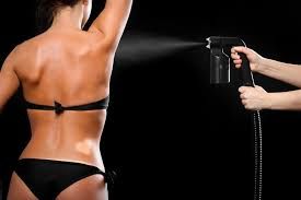 A woman in a bikini getting a spray tan on her back.