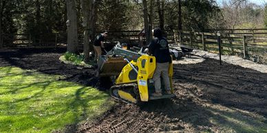 landscapers are spreading and leveling topsoil to prepare the ground for landscaping or grass seedin