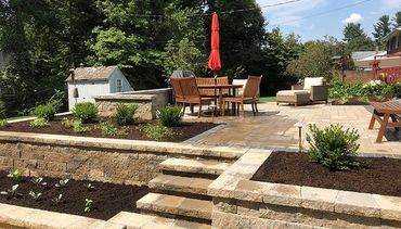 Paver patio with mulch beds inside of a retaining wall