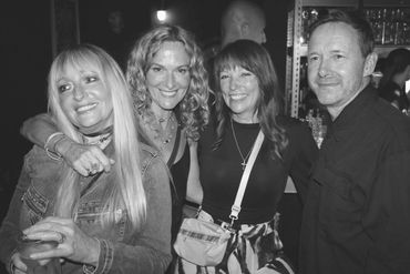 Four friends smiling and posing together in a lively night setting.