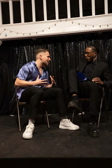 Two men engaged in a lively conversation on stage.