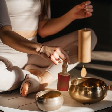 Person using Tibetan singing bowls for meditation or sound therapy.
