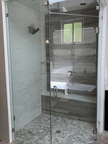 Modern glass shower enclosure with tiled walls and floor.