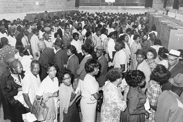 A large group of African Americans standing in line indoors, possibly voting.