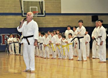 Karate instructor walking in front of a line of yellow belt students.