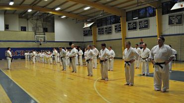 Large group of karate students performing a drill in a gym.